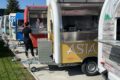 Yellow Asia food truck with two people in the background