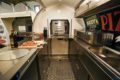 Interior pizza sales trailer with ingredients for a pizza and a pizza oven