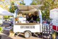 Two people stand in a sales trailer and smile at the camera