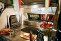 Interior of a pizza sales trailer with view of the stainless steel counters and the pizza oven