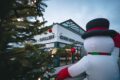 Ein aufblasbarer Schneemann steht neben einem Weihnachtsbaum vor dem Gebäude