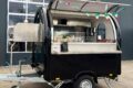 Schwarzer mobiler Pizzawagen mit geöffneter Verkaufsklappe